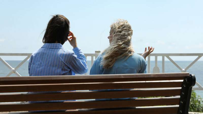 Two girls conversing on a bench.