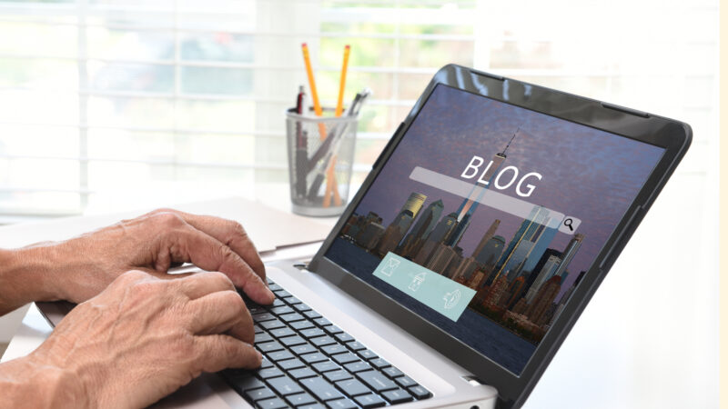Male hands typing on a laptop. Blog written across the scteen.